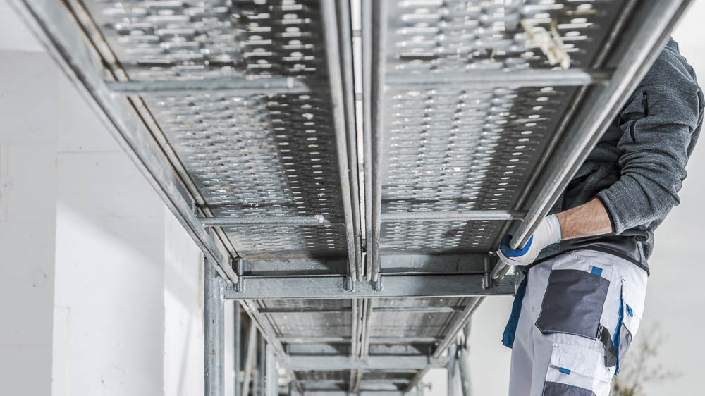 Gerüstbau Handwerker montiert Gerüstbeläge